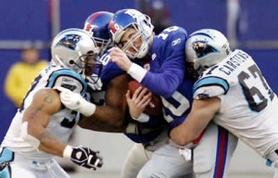 
Giants quarterback Eli Manning is sacked by Carolina's Julius Peppers, left, and Jordan Carstens for a 6-yard loss in the third quarter. Manning had four turnovers in his playoff debut. 
 (Associated Press / The Spokesman-Review)