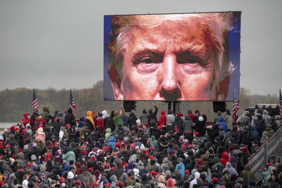 Supporters of President Donald Trump watch a video screen showing his face during a campaign event on Tuesday, Oct. 27, 2020, in Lansing, Mich.  (Nicole Hester)