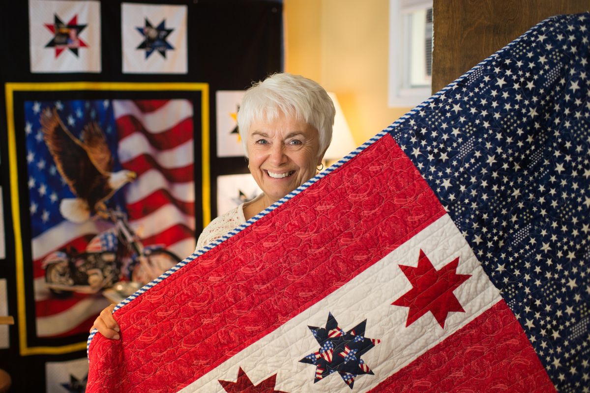 Cherrie Takenaka poses for a photo with a quilt she made with the Garland Quilts of Valor group on Thursday, June 1, 2017, Spokane, Wash. (Tyler Tjomsland / The Spokesman-Review)