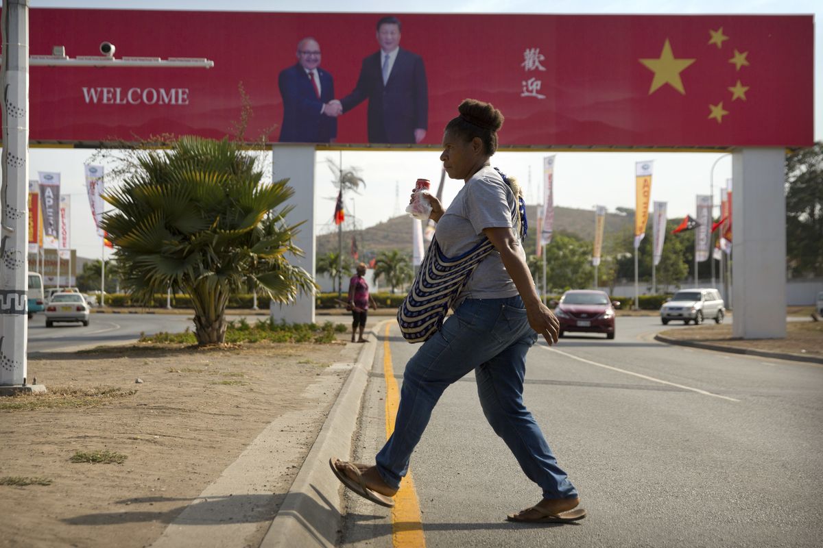 FILE - A woman crosses the street near a billboard commemorating the state visit of Chinese President Xi Jinping in Port Moresby, Papua New Guinea, Nov. 15, 2018. China wants 10 small Pacific nations to endorse a sweeping agreement covering everything from security to fisheries in what one leader warns is a “game-changing” bid by Beijing to wrest control of the region.  (Mark Schiefelbein)
