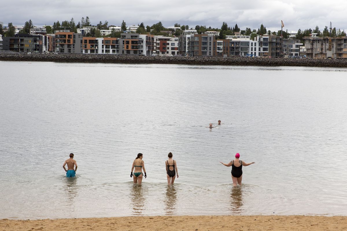 People go for a swim in the water in Nauthólsvík, a small neighbourhood in Reykjavik, Iceland Saturday Aug. 1, 2020. In Iceland, a nation so safe that its president runs errands on a bicycle, U.S. Ambassador Jeffery Ross Gunter has left locals aghast with his request to hire armed bodyguards. He