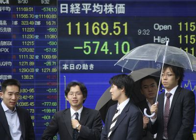A big loss on the Tokyo stock market is flashed on a digital screen in front of Japanese businessmen waiting to cross a downtown Tokyo street on Tuesday.  (Associated Press / The Spokesman-Review)