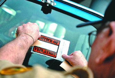 
SCOPE volunteer, Ray Westlake posts a ticket on a vehicle illegally parked in a space reserved for people with disabilities.
 (Jed Conklin / The Spokesman-Review)