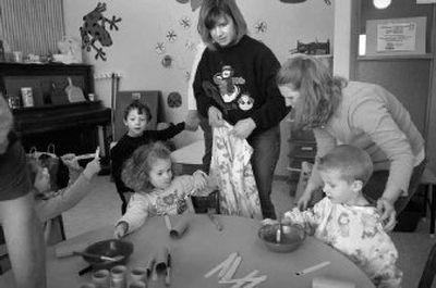 
 Parent Katie Christensen, right, and teacher Kim Devereaux, center, help preschoolers, from left, Kinsey Ellis, Eli Caballero, Teagan Whitmire and Caleb Christensen  get ready for an art project at Mead Parent Cooperative Preschool recently.  
 (Holly Pickett / The Spokesman-Review)