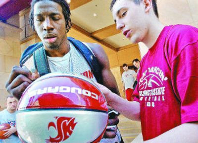 
Ivory Clark, left, autographs a ball held by Washington State University team manager Mitch Reaves before leaving the team hotel for practice Friday. 
 (Christopher Anderson / The Spokesman-Review)