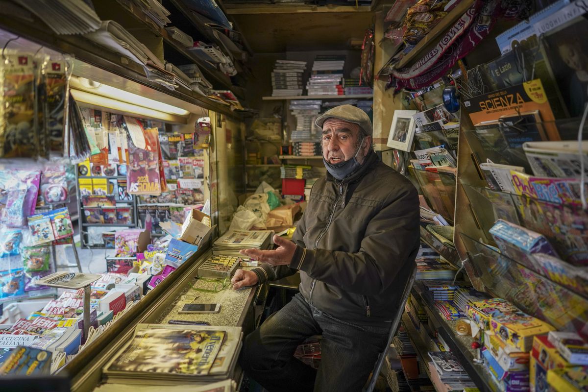 Armando Alviti, 71, sits inside his newspaper kiosk, in Rome, Friday, Dec. 4, 2020. In Italy, which has the world’s second-oldest population, many people in their 70s and older have kept working through the COVID-19 pandemic. From neighborhood newsstand dealers to farmers bring crops to market, they are defying stereotypic labels that depict the old as a monolithic category that’s fragile and in need of protection.  (Andrew Medichini)