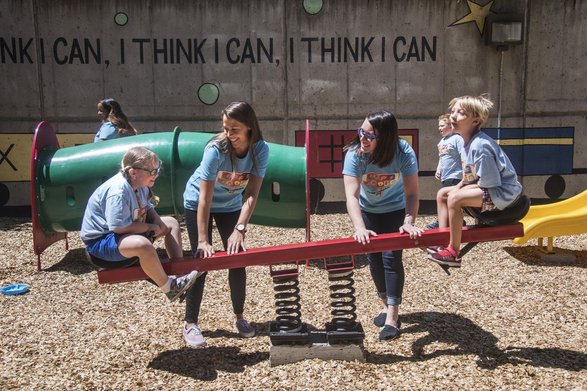 EWU graduate students Anne Monda and Kaydee Tarin assist Tabitha Kimmet and William Crocker on playground equipment at the WSU Health Sciences Building on the University District campus in Spokane on Thursday. They are all part of Camp Candoo, a camp for children with speech disorders. (Dan Pelle / The Spokesman-Review)