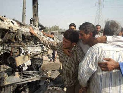 
Rashad Rashid, left, cries while touching the truck his brother Ziad Rashid was killed in after a bomb went off under it, in Baghdad on Sunday.
 (Associated Press / The Spokesman-Review)