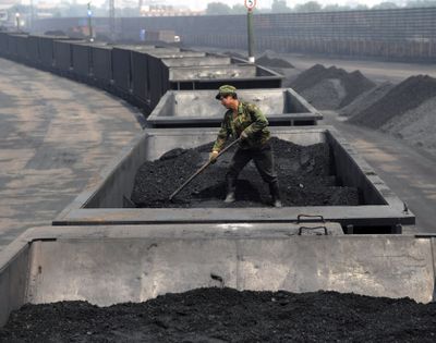 A worker levels the coal on a freight train in Taiyuan in northern China’s Shanxi province on July 31. (Associated Press)