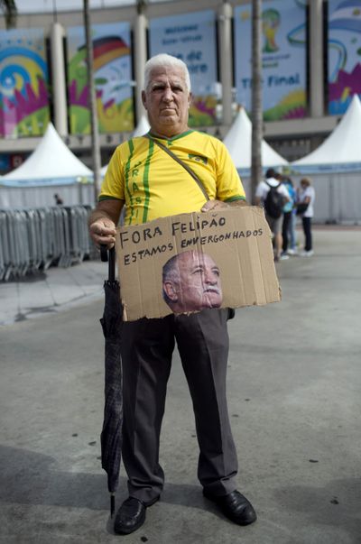 A soccer fan holds a sign made from cardboard bearing an image of Brazilian head coach Luis Felipe Scolari with a message that reads in Portuguese; “We are ashamed. You need to resign Felipe,” in front of the Maracana Stadium in Rio de Janeiro on Saturday. (Associated Press)