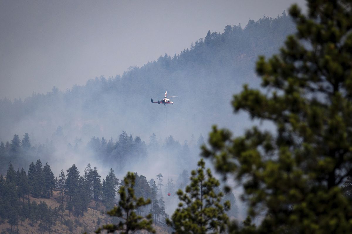 A helicopter pilot prepares to drop water on a wildfire burning in Lytton, B.C., on Friday, July 2, 2021. Officials on Friday hunted for any missing residents of a British Columbia town destroyed by wildfire as Canadian Prime Minister Justin Trudeau offered federal assistance.  (Darryl Dyck)