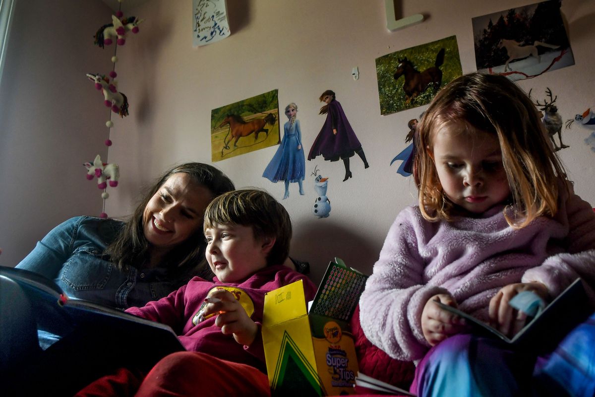 Eileen Grimes works on “The Us Journal” with her son Liam, 7, while her daughter Lily, 4, looks through a book at their home in the Perry District on Tuesday. Grimes created “The Us Journal” as an interactive book geared to 5- to 9-year-olds.  (Kathy Plonka/The Spokesman-Review)