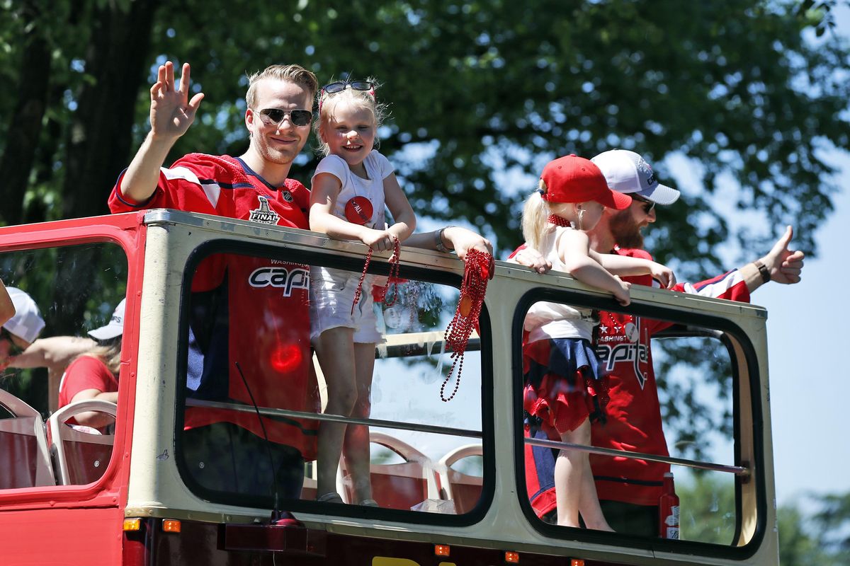 Washington Capitals center Lars Eller, left, from Denmark, and goaltender Braden Holtby, right, hold their children during a victory parade, Tuesday, June 12, 2018, in Washington. (Alex Brandon / AP)