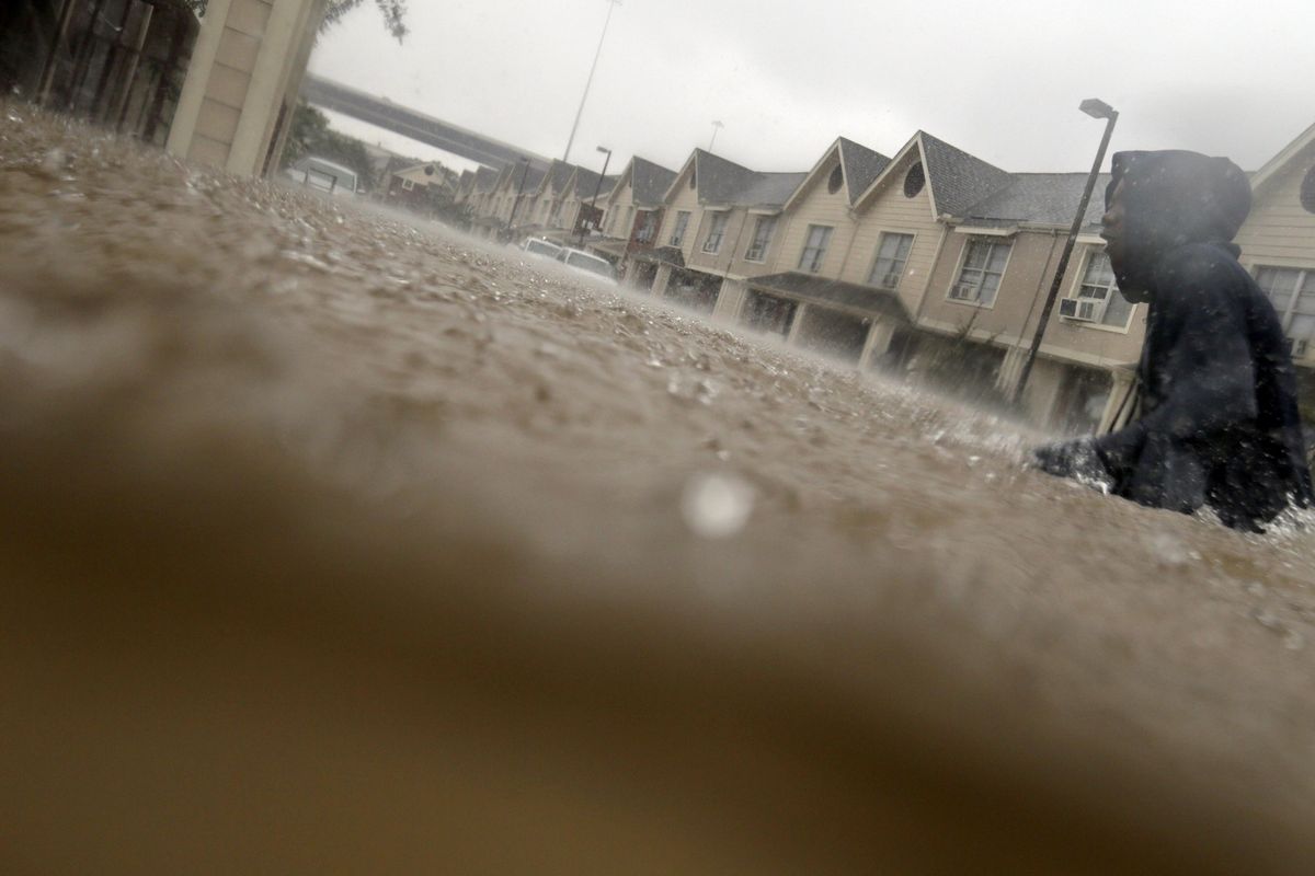 A child makes his way through floodwaters from Tropical Storm Harvey while checking on neighbors at his apartment complex in Houston, Sunday, Aug. 27, 2017. The remnants of Hurricane Harvey sent devastating floods pouring into Houston Sunday as rising water chased thousands of people to rooftops or higher ground. (LM Otero / Associated Press)