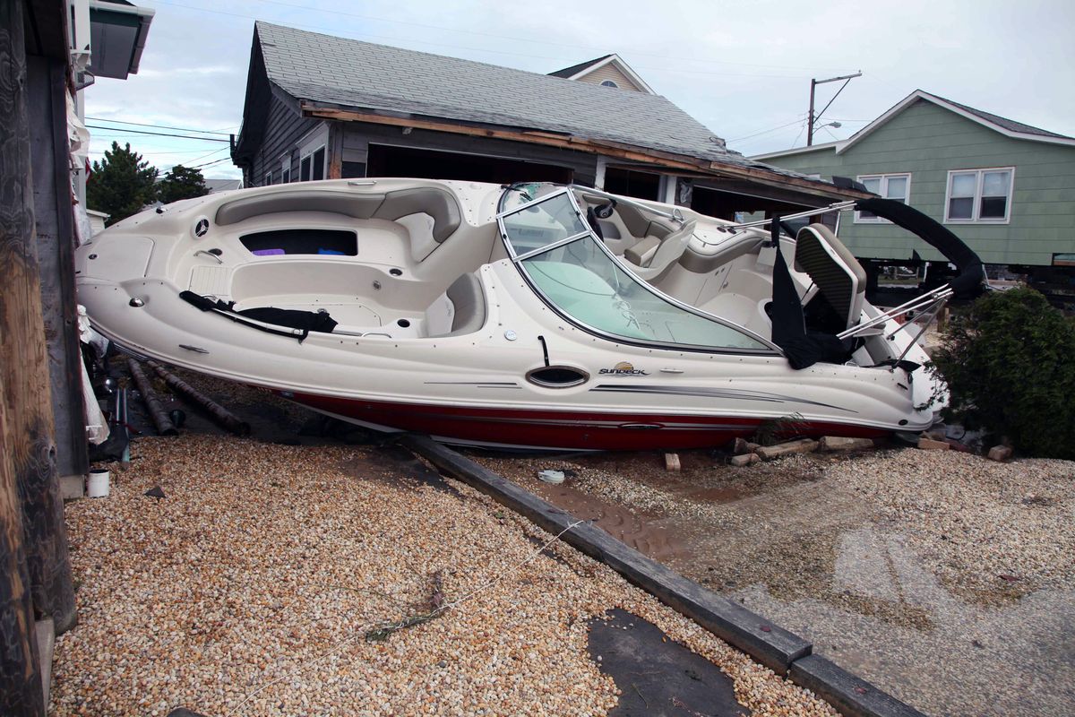A boat rests up against a house in the wake of superstorm Sandy Wednesday Oct. 31, 2012 in Cedar Bonnet Island, NJ. Power is still out and residents who evacuated the island are still not being allowed back in. Sandy was being blamed for at least six deaths across the state of New Jersey plus power outages that at their peak Monday affected 2.7 million residential and commercial customers. (Robert Ray / Associated Press)