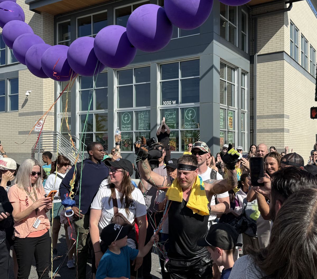 Brenton Sconce celebrates with family, friends and spectators after crossing the Bloomsday finish line on Monday, north of the Monroe Street Bridge. Sconce bear-crawled the race. (Erik Etherton/The Spokesman-Review)