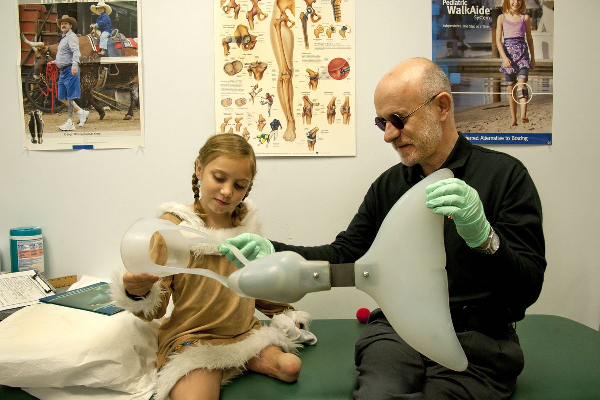 Kevin Carroll, a prosthetist whose development of the first prosthetic tail for a dolphin helped inspire the movie “Dolphin Tale,” pays a visit to Isabelle James, 9. Isabelle, who lives in North Idaho, lost her leg in a lawn mower accident. (Dan Pelle)