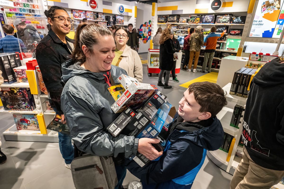 Ethan Hinshaw, age 9, helps his mom Hannah wrangle boxes of LEGO products as they wait in the busy checkout line. The LEGO Store had its grand opening Friday at River Park Square.  (COLIN MULVANY/THE SPOKESMAN-REVIEW)