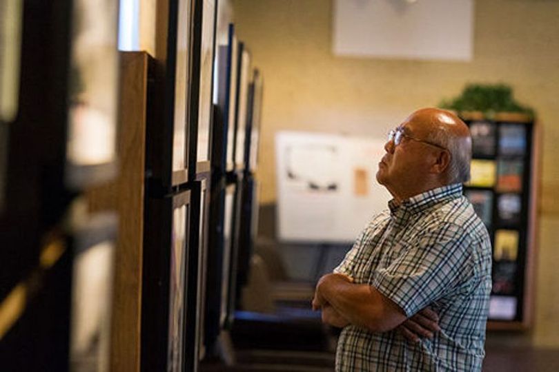 Keiji Shimizu studies World War II era photographs of a Japanese internment camp in Idaho at the Human Rights Education Institute’s “Uprooted” exhibit Monday in Coeur d’Alene. (Shawn Gust / Coeur d'Alene Press)