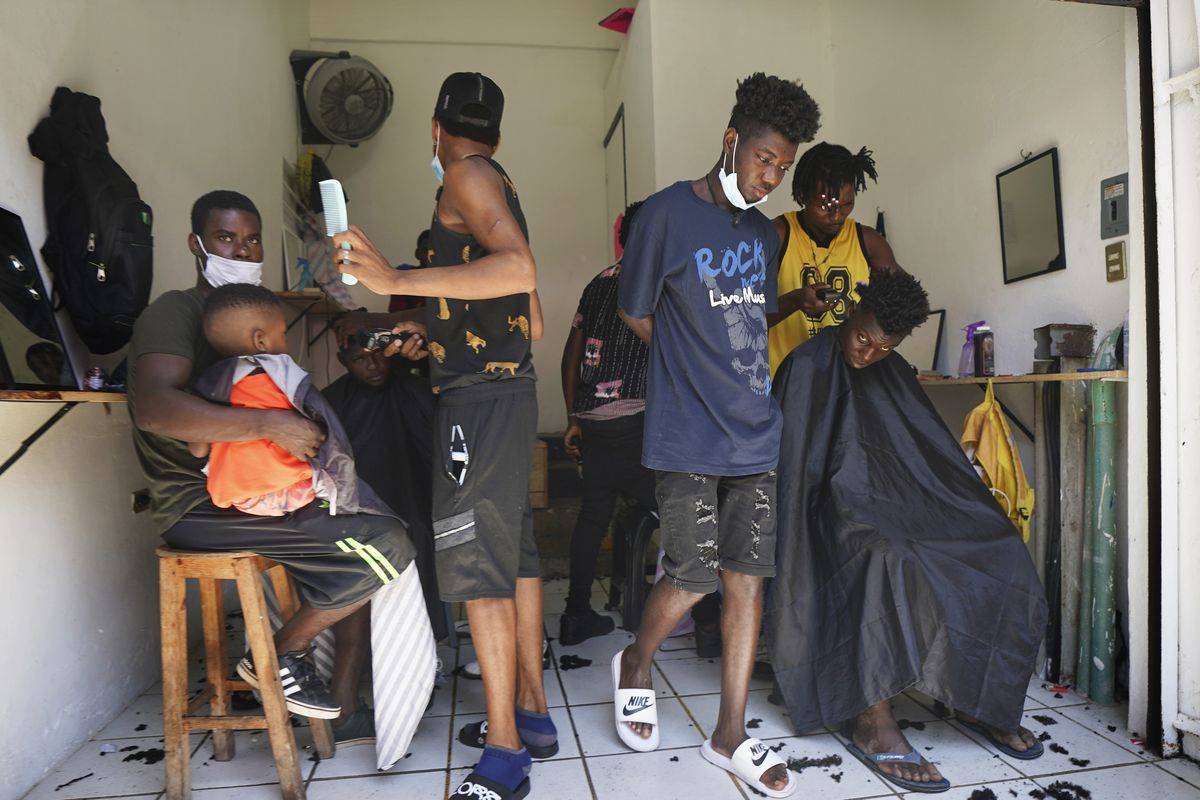 FILE - In this Sept. 3, 2021 file photo, Haitian migrants gather in a makeshift barbershop in Tapachula, Mexico. Thousands of mostly Haitian migrants have been stuck in the southern city of Tapachula, many waiting here for months and some up to a year for asylum requests to be processed.  (Marco Ugarte)