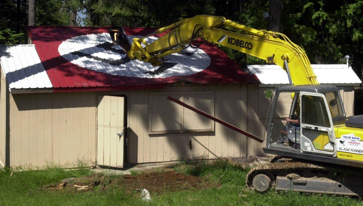 An excavator digs into a dilapidated cook shack which had a swastika on the roof at the Aryan Nations compound in Garwood Wednesday, May 24, 2001. (Jesse Tinsley/Spokesman-Review File Photo)