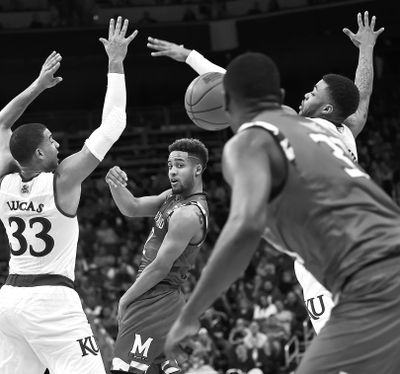 Maryland guard Melo Trimble whips a pass to a teammate between Kansas defenders Landen Lucas, left, and Wayne Selden Jr. during first-half action in Louisville, Kentucky. (John Flavell / Associated Press)