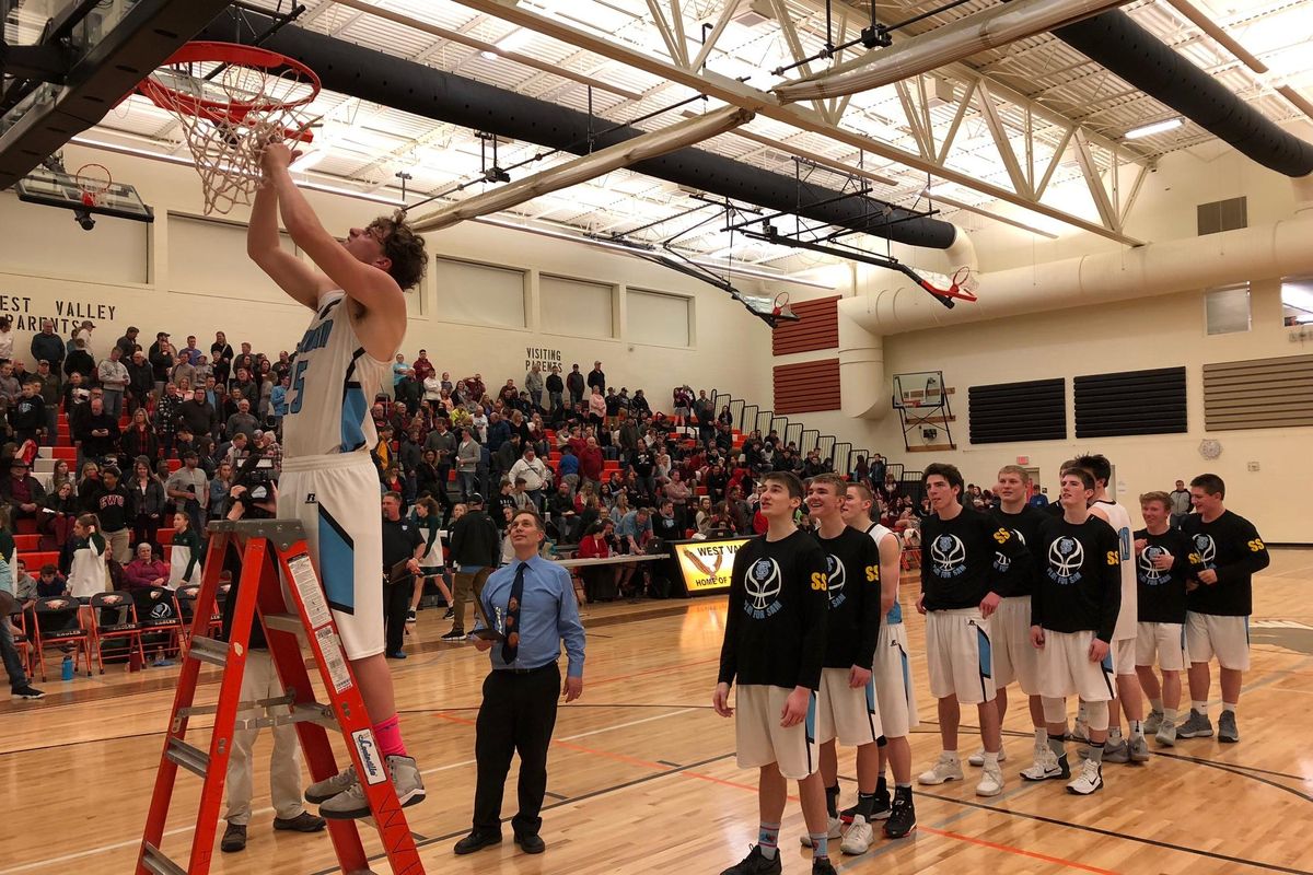 Jimmie Pierce cuts down the net following Freeman’s 57-41 district title win over Lakeside at West Valley HS on Wednesday. (Dave Nichols / The Spokesman-Review)