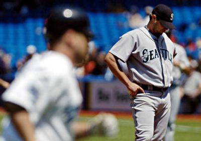 
Seattle pitcher Joel Pineiro, right, hangs his head as Toronto's Shea Hillenbrand rounds the bases to score on his three-run homer during the third inning. 
 (Associated Press / The Spokesman-Review)