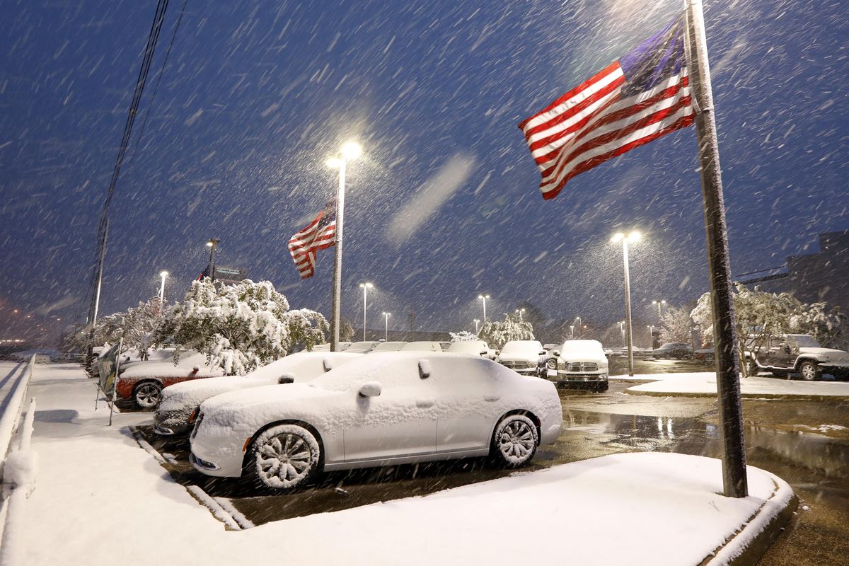 American flags wave as snow falls, blanketing vehicles in a car sales lot, Friday, Dec. 8, 2017, in Jackson, Miss. (Rogelio V. Solis / Associated Press)