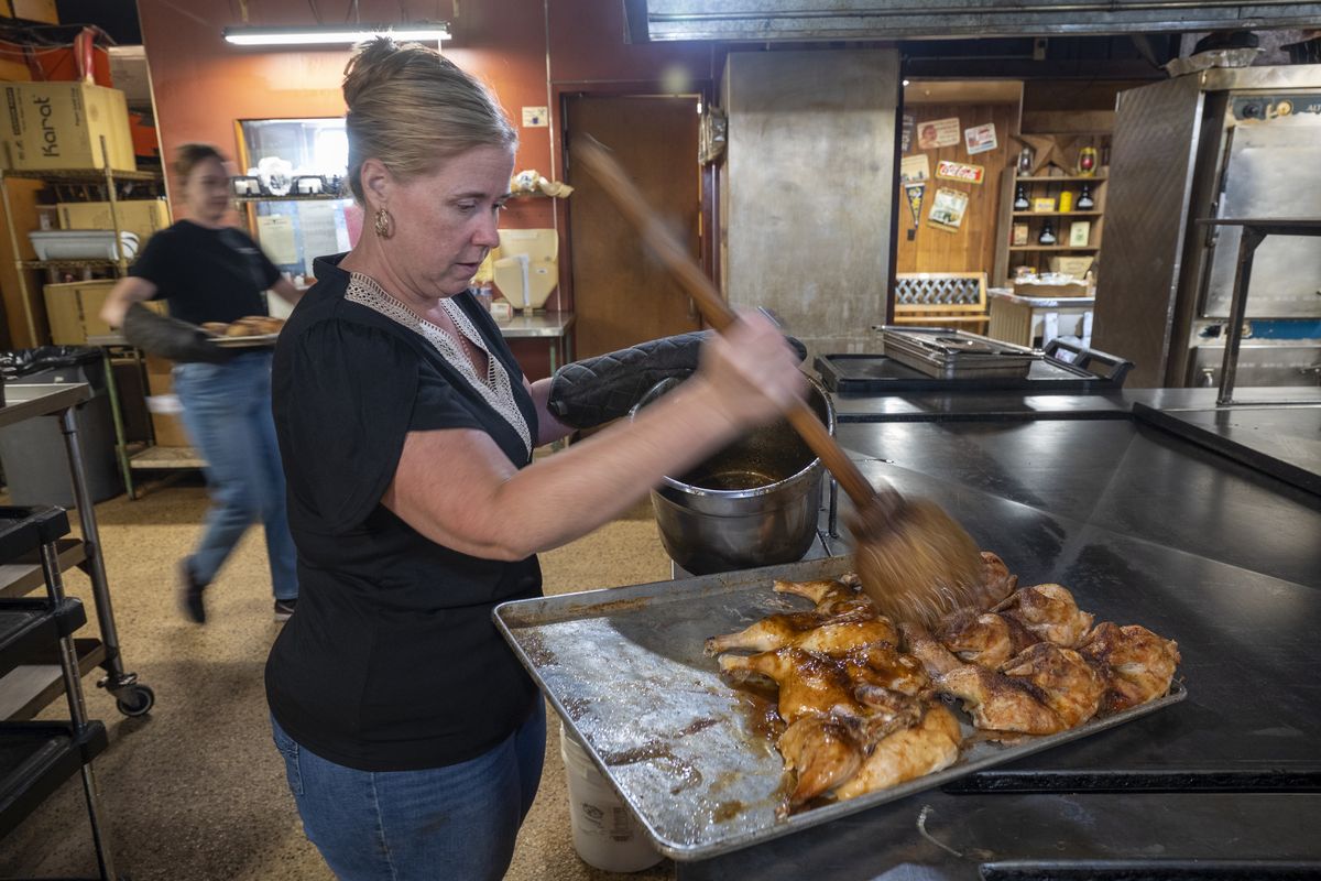 Erin Everhart mops barbecued chicken quarters with barbecue sauce at the Longhorn Barbecue restaurant at 2315 N. Argonne Road. Everhart and Zac Smith are now owners and operators of the restaurant, which has belonged to Bill Miller and Randy Ingraham. The restaurants and the large production center that makes barbecue foods and sauces for sale in grocery stores and retail outlets like Costco all started with the Lehnertz brothers who moved to Spokane from southern Texas. The original Lehnertz brothers have died, but elements of ownership are still traceable to the Lehnertz family.  (Jesse Tinsley/The Spokesman-Revi)