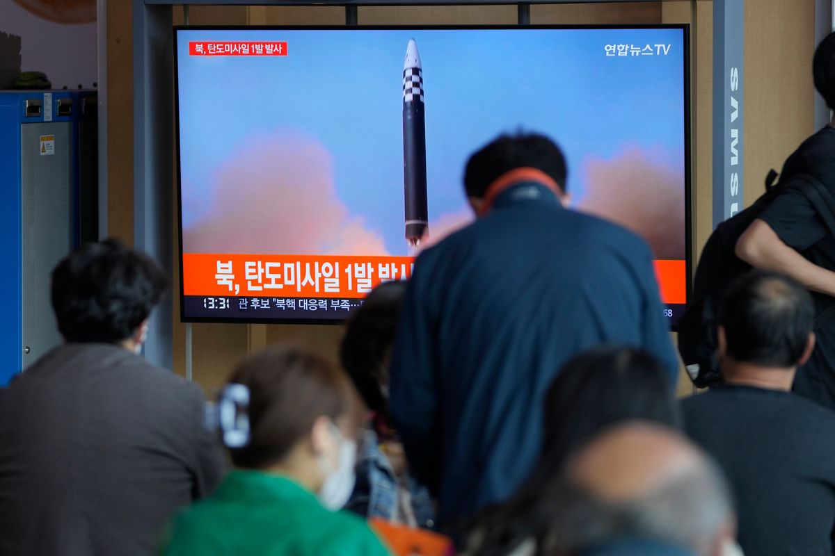 People watch a TV screen showing a news program reporting about North Korea
