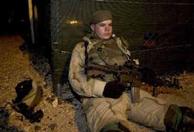 
During a break in patrolling, Spc. Chris Hotvedt  of Coeur  d' Alene rests with his M-4 carbine at the ready. 
 (The Spokesman-Review)