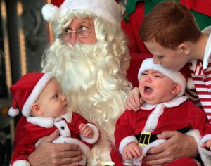 Santa looks for a little help during a photo as Cameron Dirr, center right, 11 months, of Green Township, starts to cry as his older bother Jaycob, right, 11, attempts to calm him on Saturday, Dec. 12, 2009, in Delhi, Ohio. Cousin Timothy Kemplin, 9 months, of Green Township, looks on. (Ernest Coleman / The Cincinnati Enquirer)