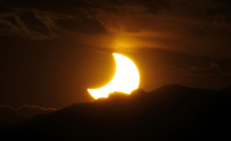In this May 20, 2012, file photo, the annular solar eclipse is seen as the sun sets behind the Rocky Mountains from downtown Denver. Hundreds of thousands of people are expected to visit eastern Idaho for the solar eclipse on Aug. 21, and that could have a significant impact on the state’s highway system. (David Zalubowski / AP)