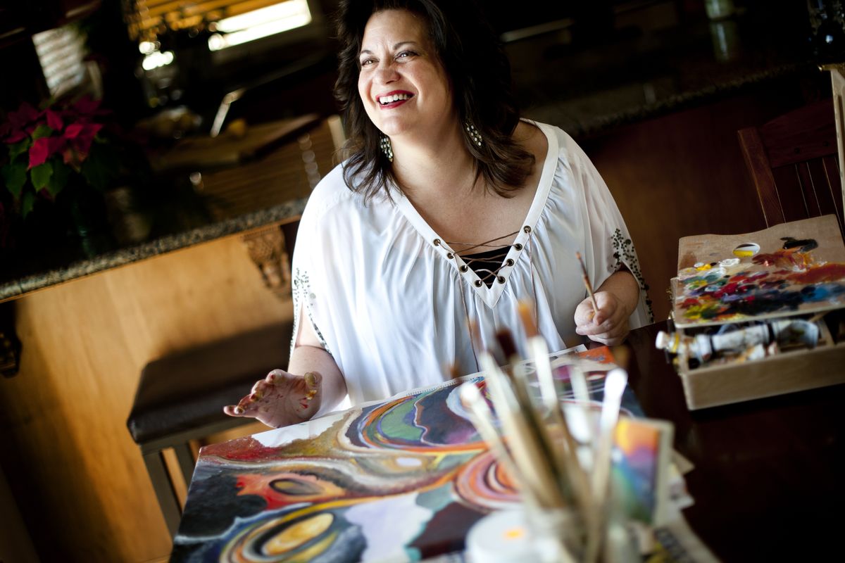 Donna Preston began painting a few years ago. “I don’t think about it. I just go with it. It’s how I ‘check out,’ ” she said. She is shown May 21 at her home near the Eagle Ridge housing development. (Tyler Tjomsland)
