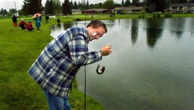 
Albert Wallace, of Post Falls, tries to get a grip on the fish he caught Saturday at Ponderosa Springs Golf Course in Coeur d'Alene. 
 (Christopher Anderson / The Spokesman-Review)