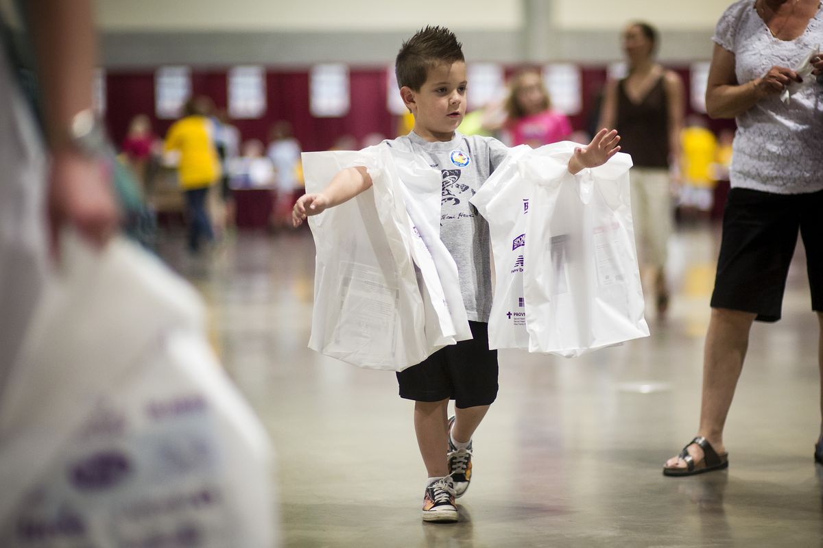 Zak Hendrix, 4, helps his mother, Tricia Hendrix, carry race packets for seven relatives at the Bloomsday Trade Show on Friday. (Colin Mulvany)