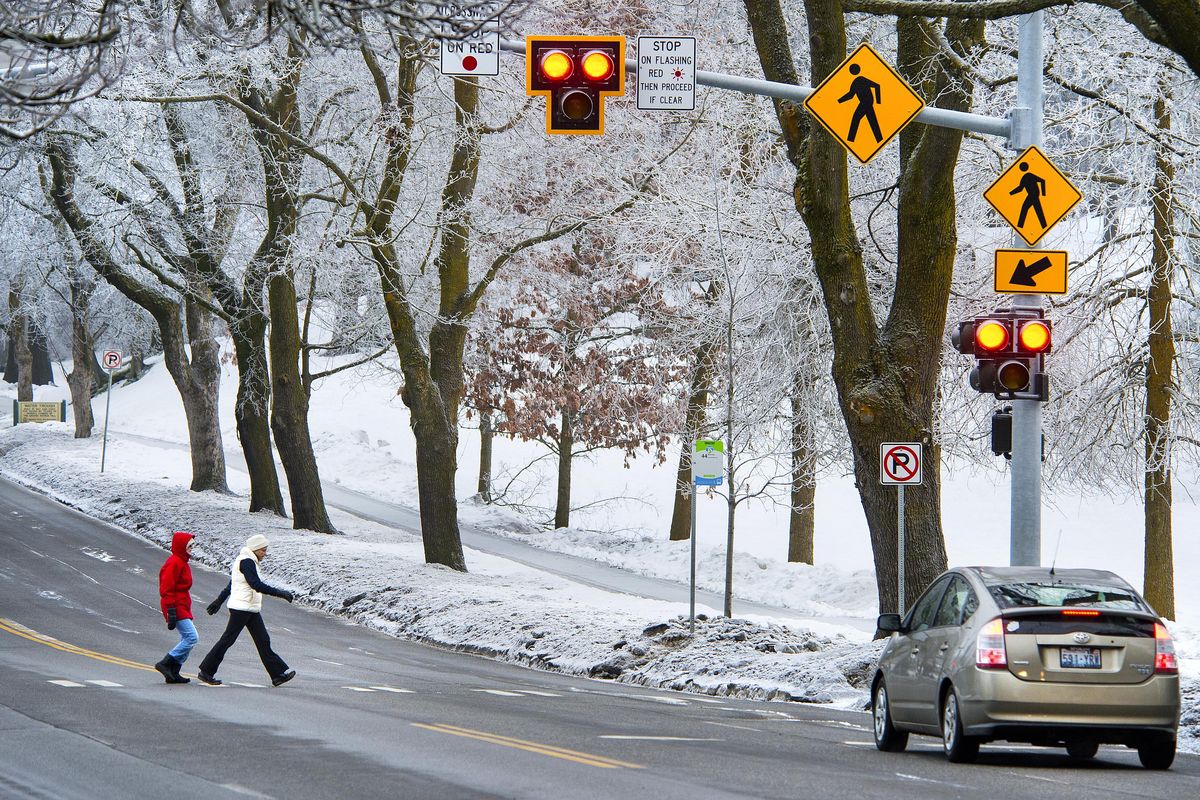 Karen Getman, left, and her walking partner, Cathy MacGillivray, cross Grand Boulevard at 18th Street with the help of HAWK beacon traffic control device on Feb. 23 in Spokane. (Dan Pelle / The Spokesman-Review)