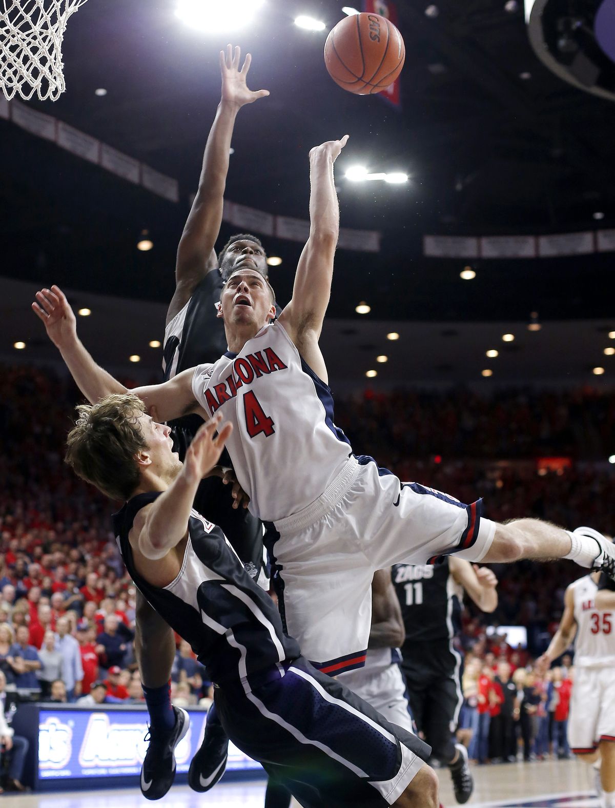 Gonzaga forward Domantas Sabonis, bottom, draws the foul on Arizona guard T.J. McConnell (4) as Gonzaga guard Gary Bell Jr., back, defends, during the second half of an NCAA college basketball game, Saturday, Dec. 6, 2014, in Tucson, Ariz. (Rick Scuteri / Fr157181 Ap)