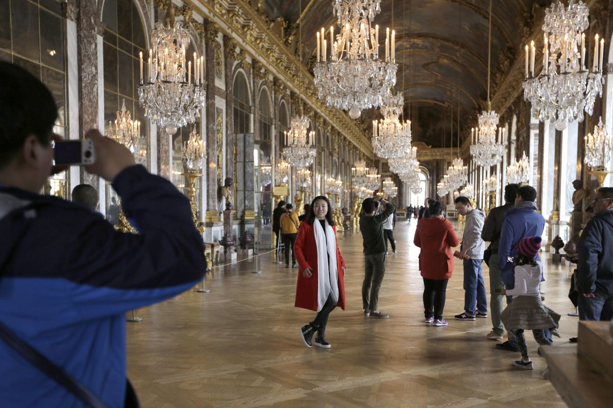 FILE - In this Nov. 17, 2015, file photo, visitors pose inside the Hall of Mirrors in the Versailles castle in Versailles, west of Paris. Rick Steves' summer travel tips include getting tickets in advance for major attractions so you can skip the line and avoid the crowds, and following local cultural customs to beat the heat, such as taking an afternoon siesta or dining late in the evening when it's cooler. (AP Photo/Amr Nabil, File) ORG XMIT: NYLS210 (Amr Nabil / AP)