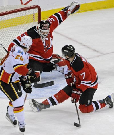 Devils goalie Martin Brodeur deflects a shot by Flames’ Curtis Glencross.  (Associated Press / The Spokesman-Review)