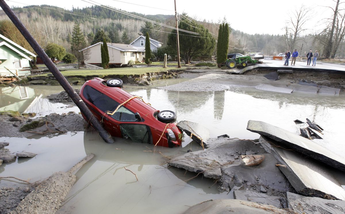 A van lies overturned in front of two houses knocked partially off their foundations on state Highway 202 just outside Fall City, Wash., on Friday.  (Associated Press / The Spokesman-Review)