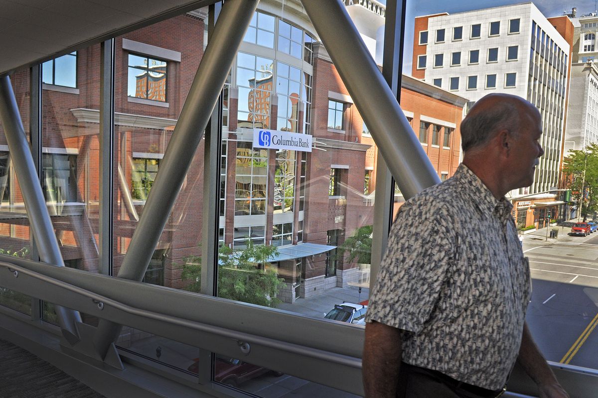 Rick Melanson crosses the Riverside Avenue skywalk as a new sign on the front of the former Bank of Whitman building in downtown Spokane announces the change to Columbia Bank on Monday. (Christopher Anderson)
