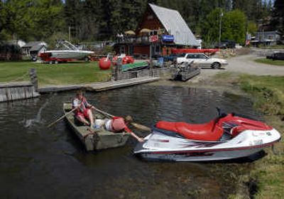 
Daniel Schule, 12, rows hard while his friend, Austin Smith, 12, pushes off to avoid a jet ski at the launch of Newman Lake Resort, Sunday. New owners Susan and Rudy Schuler have remodeled the store and plan for a new boat launch with marina, docks and fuel. The 1.8 acre resort features 600 feet of shoreline. 