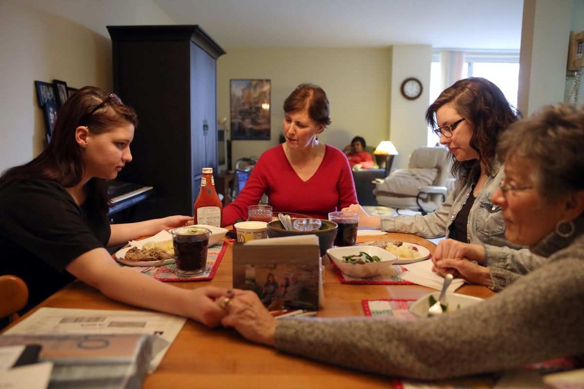 The Rev. Julie Harley, 52, center, leads a prayer with her daughters Emma, 19, left, Rachel, 21, second from right, and parishioner Ann Armstrong on Jan. 23 in Oak Park, Illi. The pastor is stepping down at First United Church of Oak Park to focus on her battle with ALS.