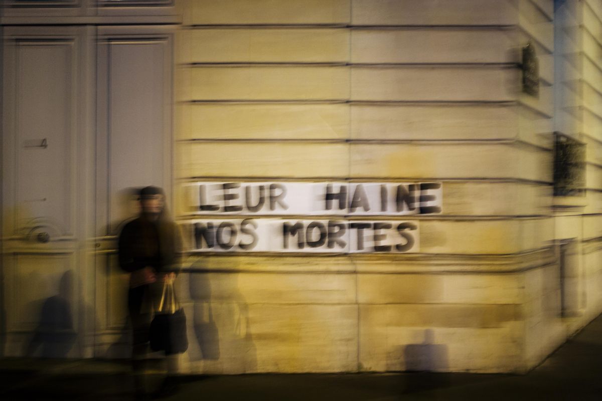 In this Nov. 8 2019 photo, Sarah stands next to slogan reading “Their hate, our dead” in Paris. Under cover of night, activists have glued slogans to the walls of buildings to draw attention to domestic violence, a problem French President Emmanuel Macron has called “France’s shame.” (Kamil Zihnioglu / Associated Press)