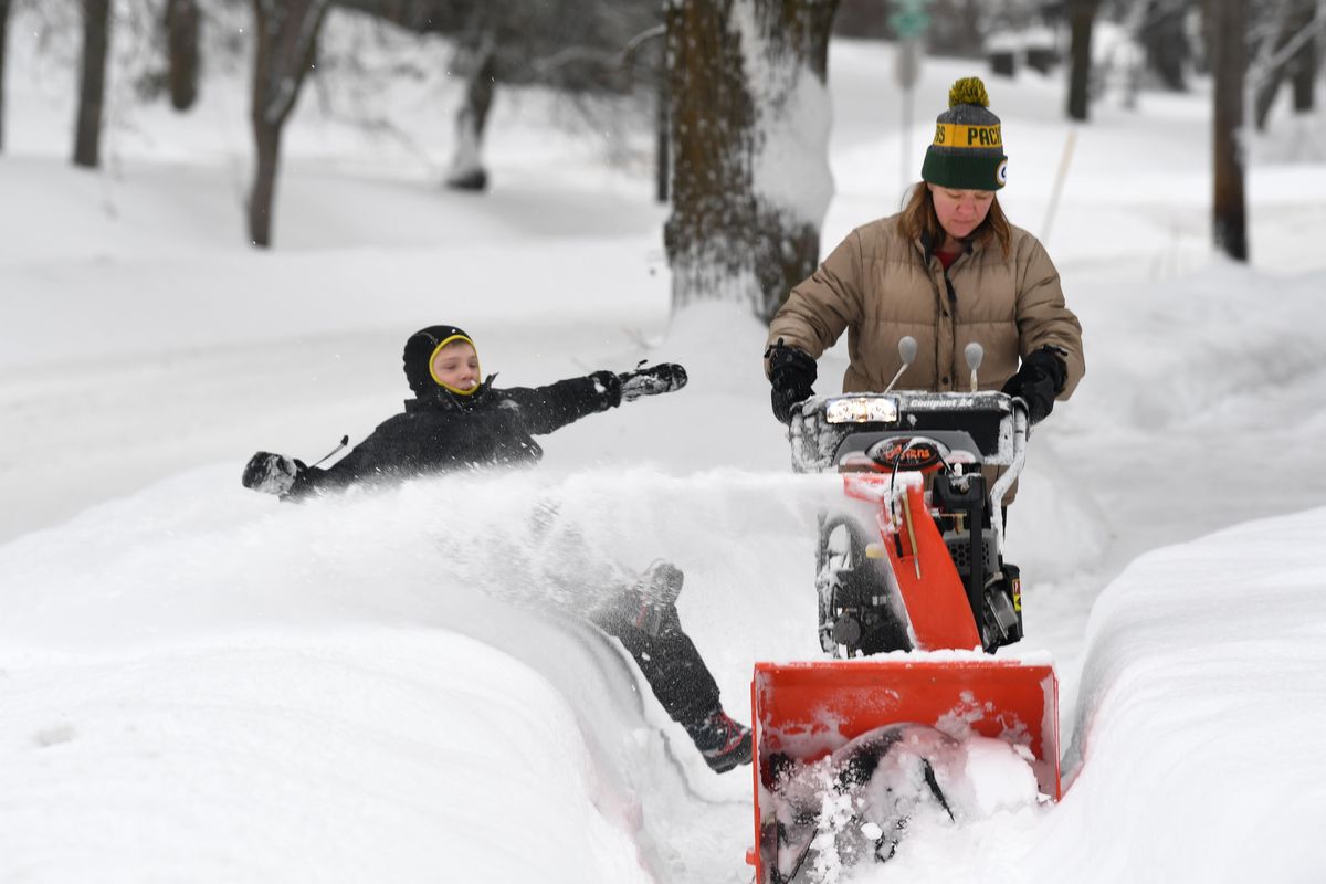 Amanda Roggenbauer runs a snowblower past several homes in her neighborhood while her son, Erik Roggenbauer, 8, dives into the snow bank for fun Monday, Jan. 9, 2017 along Rockwood Blvd. on the South Hill of Spokane. JESSE TINSLEY jesset@spokesman.com (Jesse Tinsley / The Spokesman-Review)