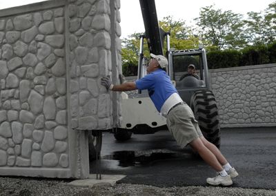 Liberty Lake golf course pro Kit DeAndre helps install precast concrete panel fence walls for the new golf cart enclosure.  (J. BART RAYNIAK / The Spokesman-Review)