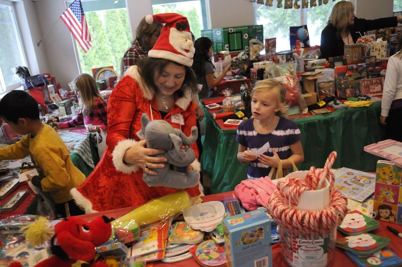 Pasadena Park Elementary volunteer Cheri Reed helps third-grader Grace Peters find the perfect gift for her family at the Scholar Dollar Christmas store, which she organizes. By reading, students earn points that they can cash in to buy gifts for family members at the store.  (J. Bart Rayniak)