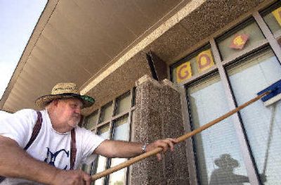 
University High custodian Howard Findley cleans pigeon droppings from the north-facing windows on the west end of University High on Tuesday. 
 (The Spokesman-Review)